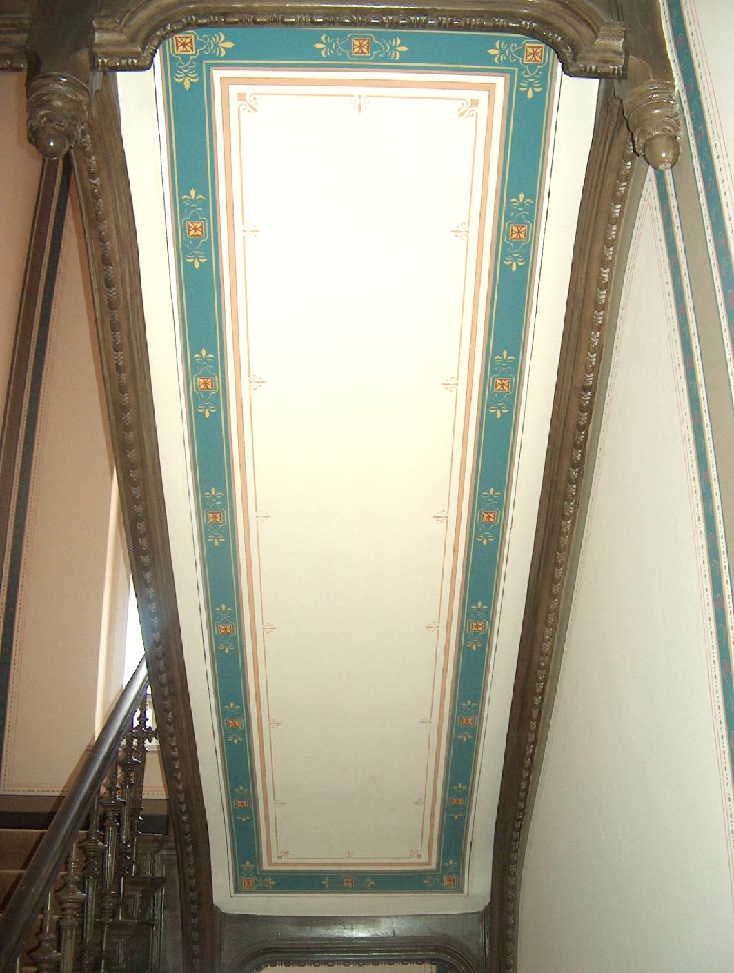 Fertiggestellte Deckenmalerei von Malermeister Schimpf. Zuvor wurde der Untergrund reversibel überarbeitet. Nach den Malerarbeiten wurde mittels Pausen und Schablonen die Deckenmalerei aufgemalt. Zu sehen ist auch die Holzmalerei bzw. Holzimitation an den Deckenwangen. Restaurierung und Gestaltung, exklusive Malerarbeiten ist der Spezialist für Deckenmalerei und Treppenhausgestaltung in Berlin. Der Malerinnungsbetrieb Norbert Schimpf beschäftigt sich fast ausschließlich wie auf diesen Bild zu sehen um vom Restaurator ischen Arbeiten für Malerei und Farbgestaltung aus den verschiedenen Epochen wie aus der Gründerzeit.